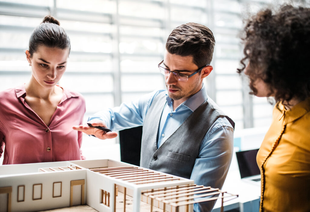Un groupe de jeunes architectes, autour de la maquette d'un bâtiment, qui parlent et échangent